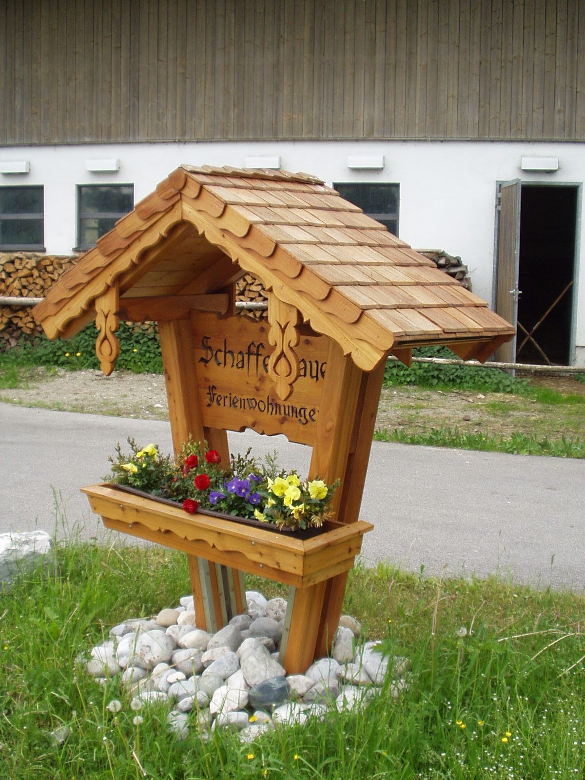 Holzbrunnen mit Blumenbeet und dekorativem Dach