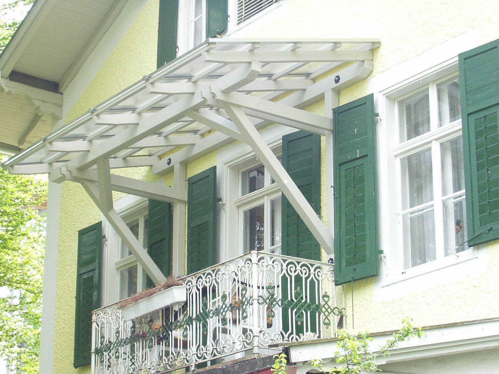 Weißer Holzbalkon mit verziertem Geländer und Überdachung