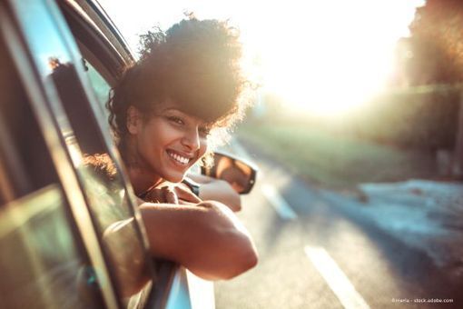 Lächelnde Person lehnt sich aus Autofenster