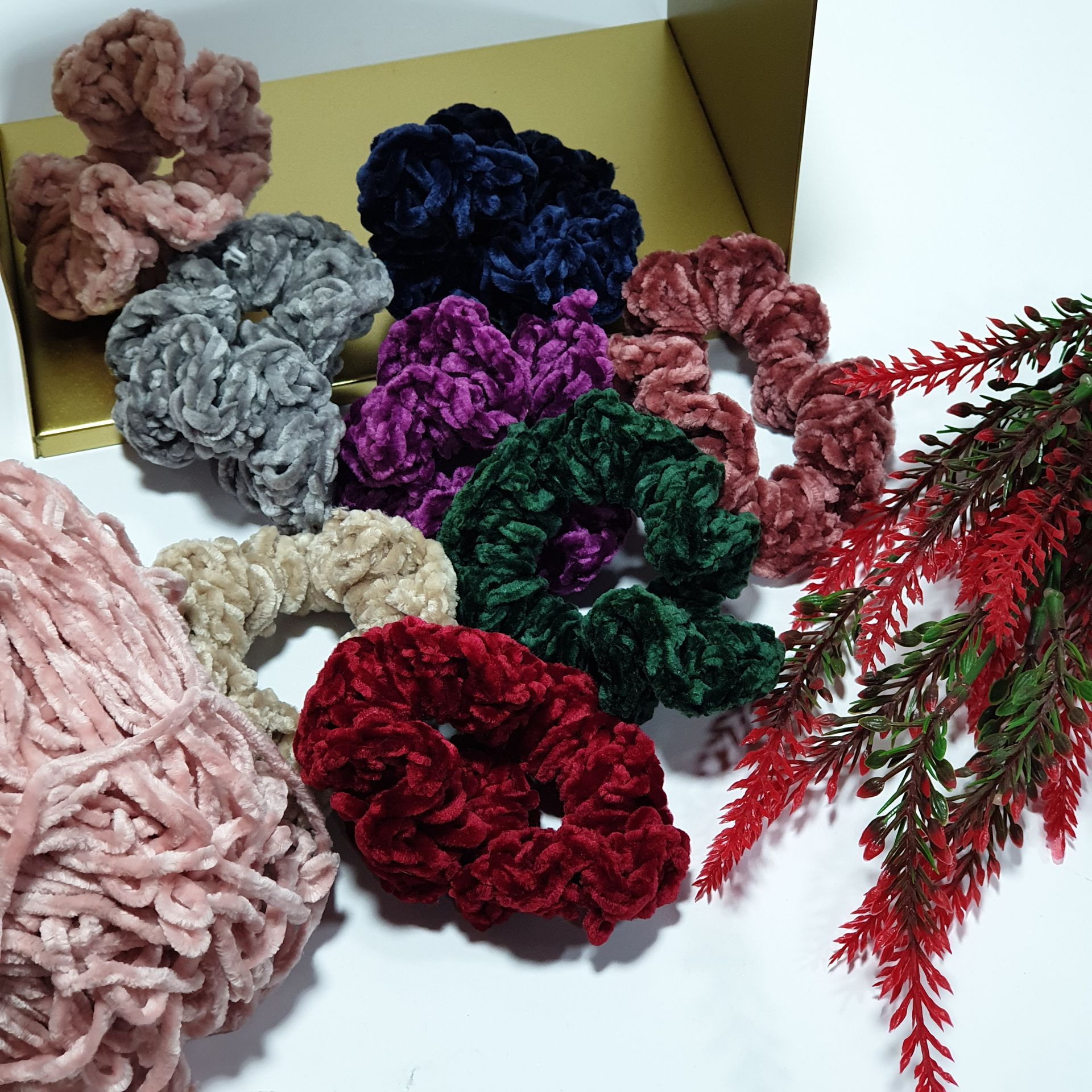 Coleteros de terciopelo en varios colores como rosa, azul y verde, con una bola de hilo y una planta roja.