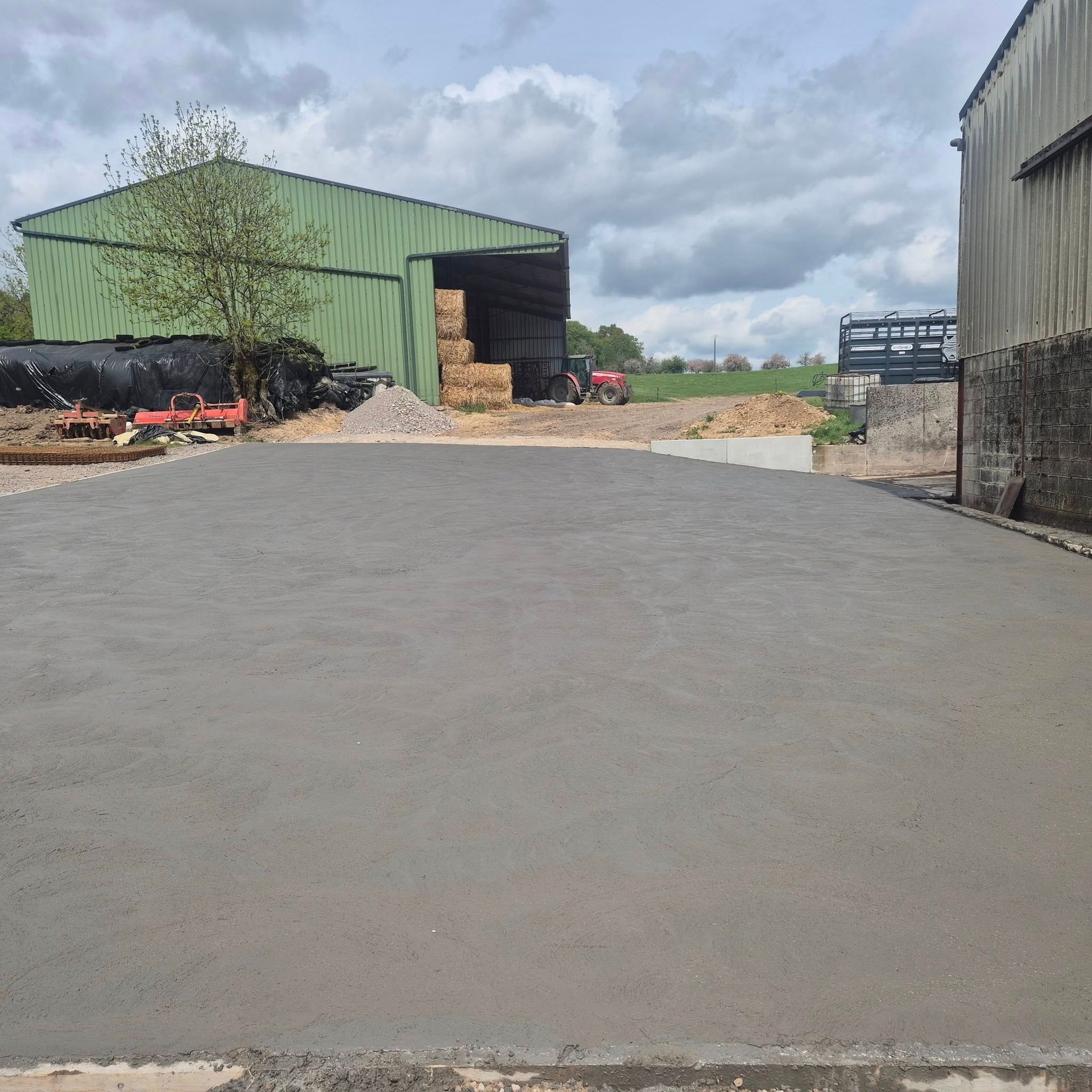 Une cour bétonnée devant un bâtiment agricole