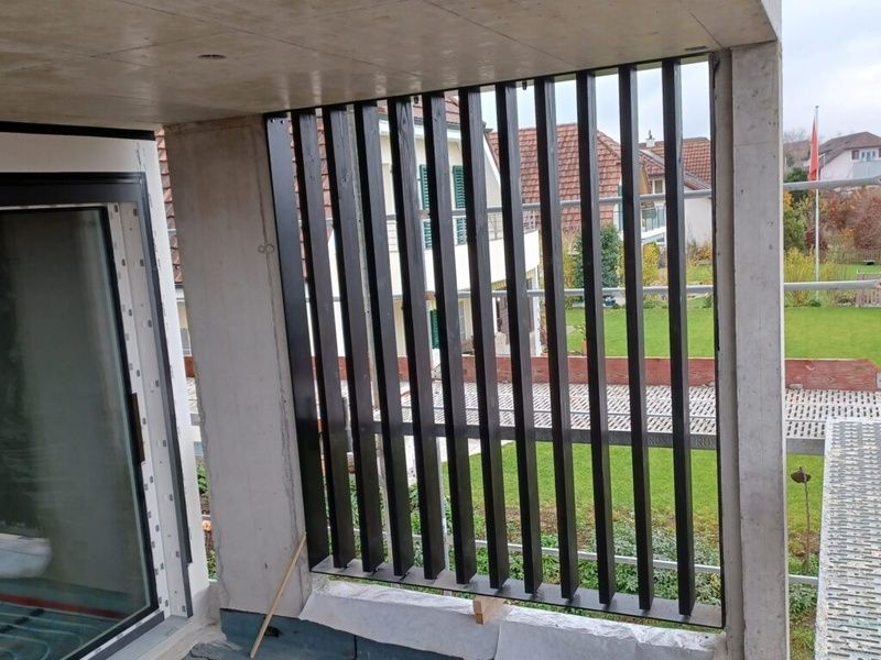 Ein Balkon mit Zaun und einem Fenster mit Blick auf ein üppiges grünes Feld. Foto von der AK Holzwerkstatt GmbH