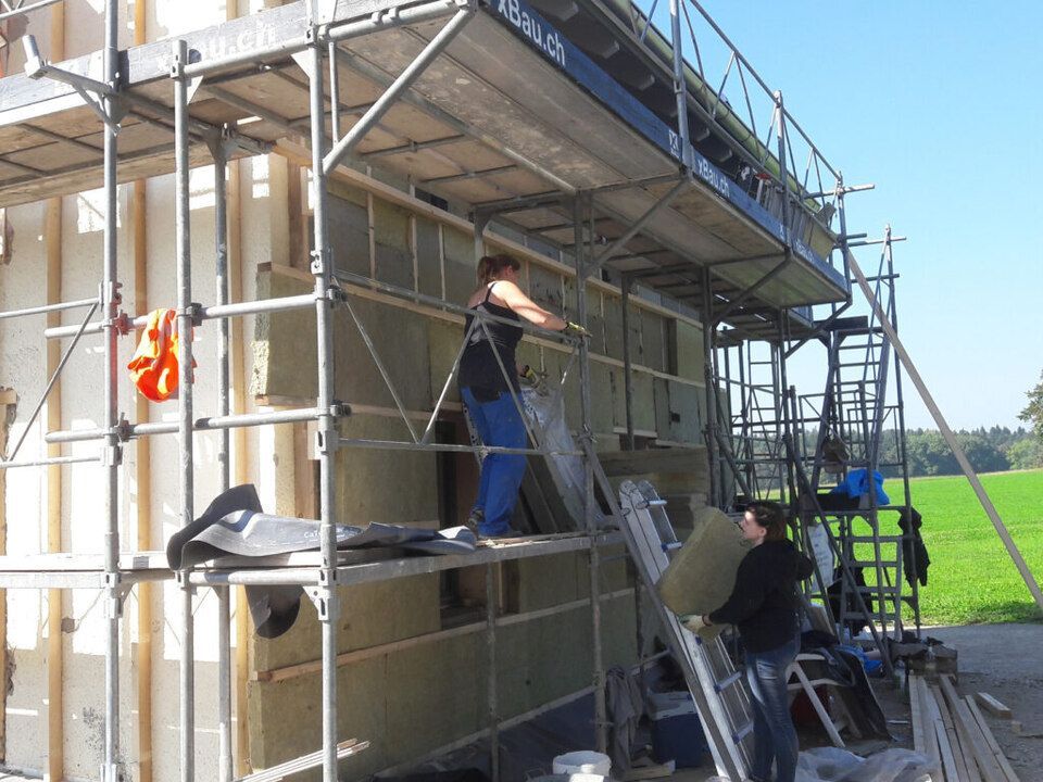 Ein Mann steht auf einer Leiter vor einem im Bau befindlichen Gebäude. Foto von der AK Holzwerkstatt GmbH