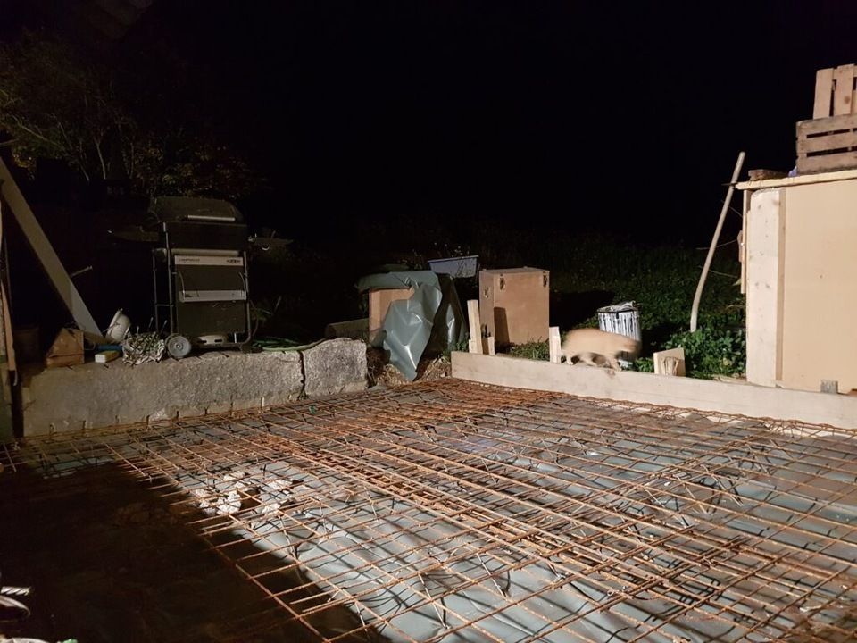 In einem Hinterhof wird nachts ein Betonboden gebaut. Foto von der AK Holzwerkstatt GmbH