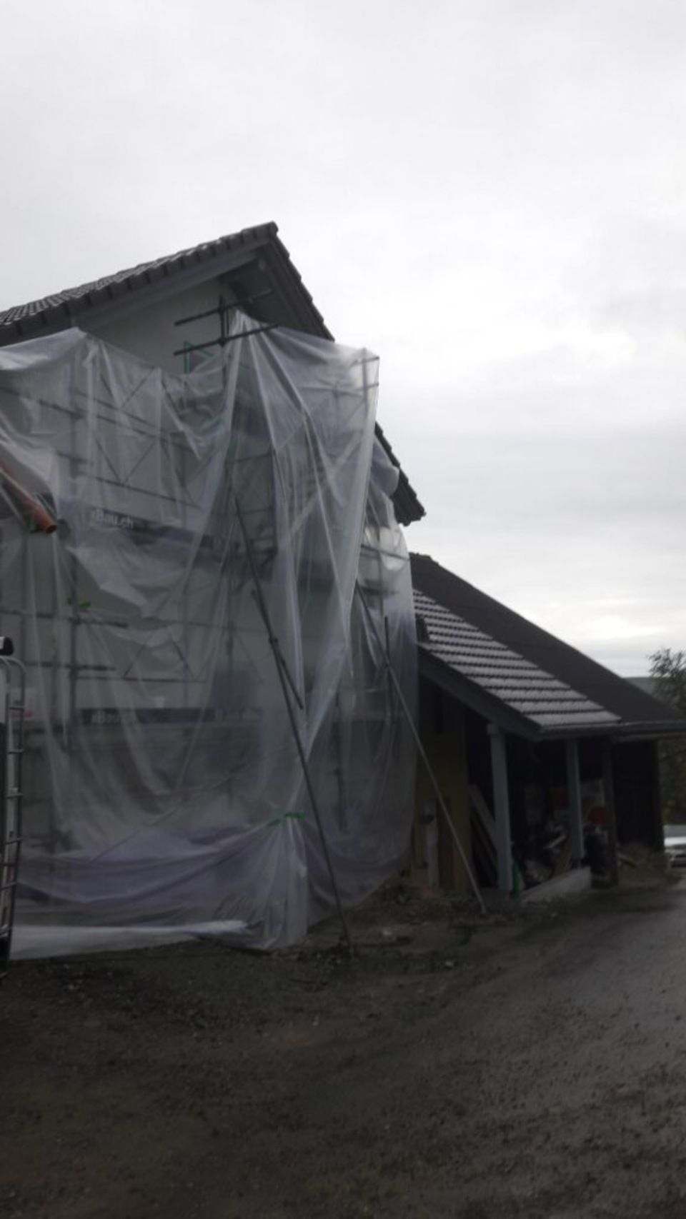 Ein grosses Gebäude ist mit Plastik und Gerüsten umhüllt. Foto von der AK Holzwerkstatt GmbH