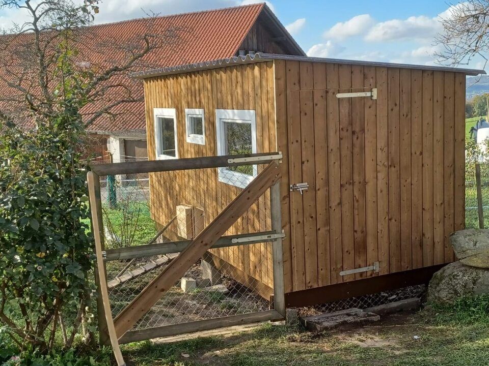 Ein Holzschuppen mit einem Zaun davor. Foto von der AK Holzwerkstatt GmbH