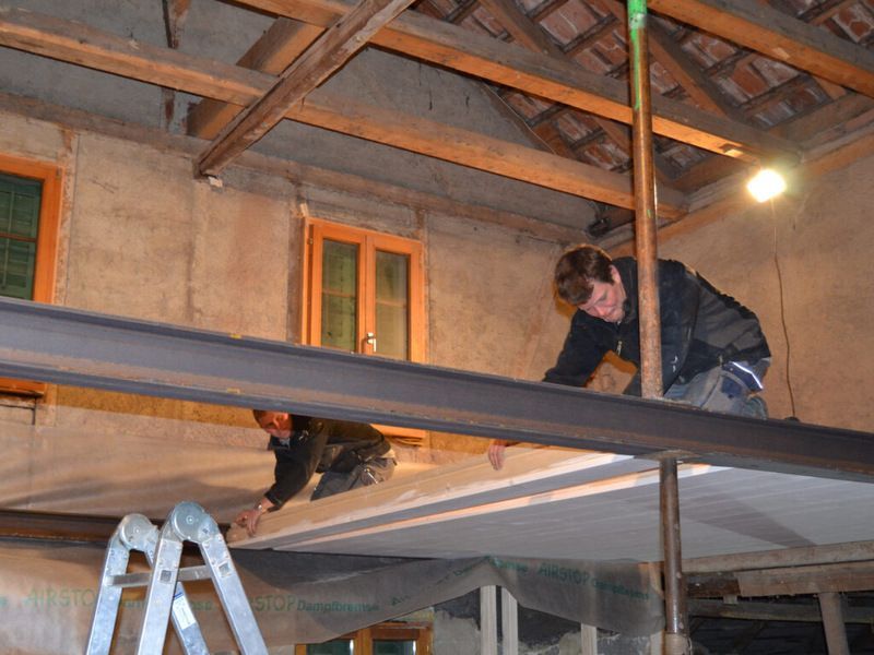 Zwei Männer arbeiten an der Decke eines Gebäudes. Foto von der AK Holzwerkstatt GmbH