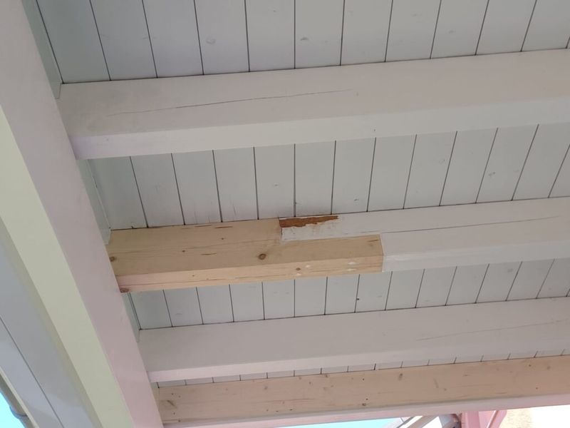 Eine Nahaufnahme einer weissen Holzdecke mit Holzbalken. Foto von der AK Holzwerkstatt GmbH