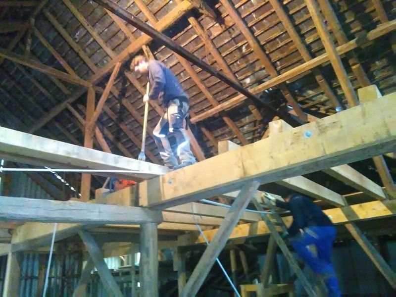 Ein Mann steht mit einem Besen auf einer Holzkonstruktion. Foto von der AK Holzwerkstatt GmbH