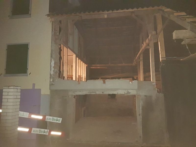 Ein Gebäude, das nachts abgerissen wird. Foto von der AK Holzwerkstatt GmbH