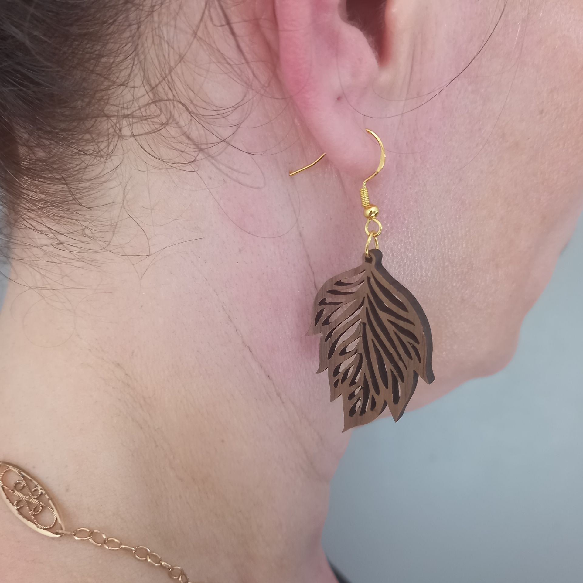Une femme portant une boucle d'oreille en bois en forme de feuille