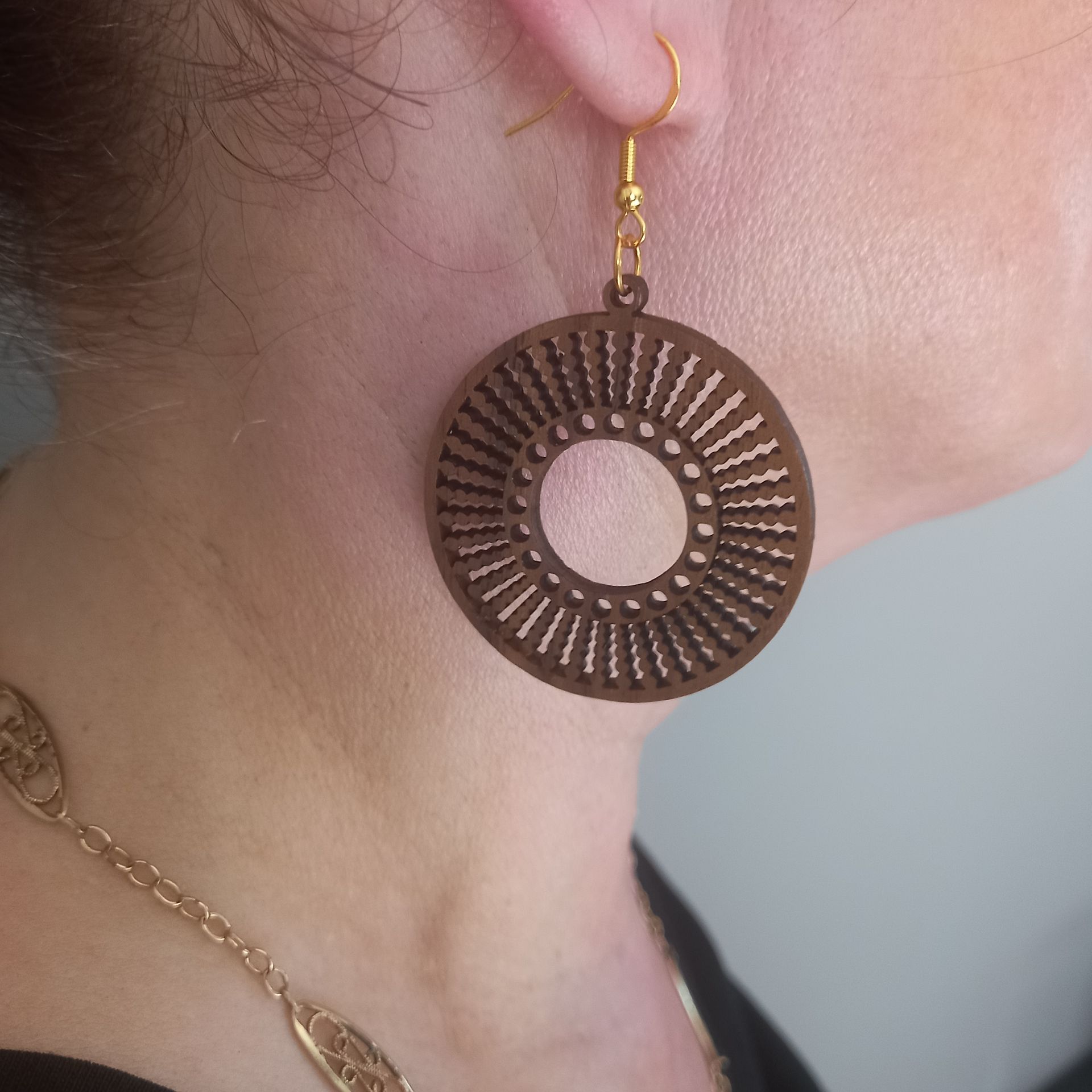 Femme portant des boucles d'oreilles rondes en bois