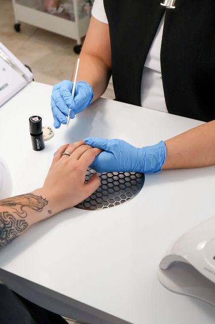 Una mujer está pintando las uñas de un hombre en un salón de uñas.