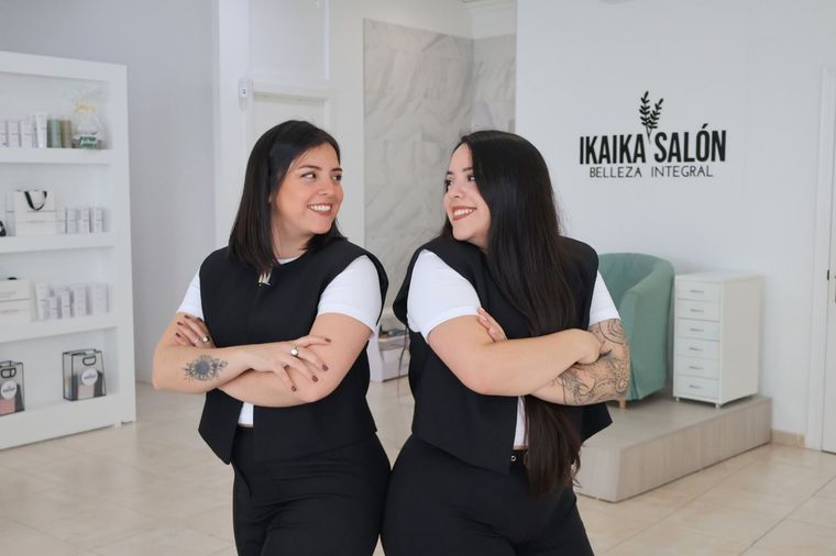 Dos mujeres están paradas una al lado de la otra en un salón con los brazos cruzados.