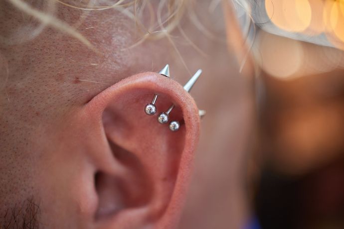 Un primer plano de la oreja de una persona con piercings.