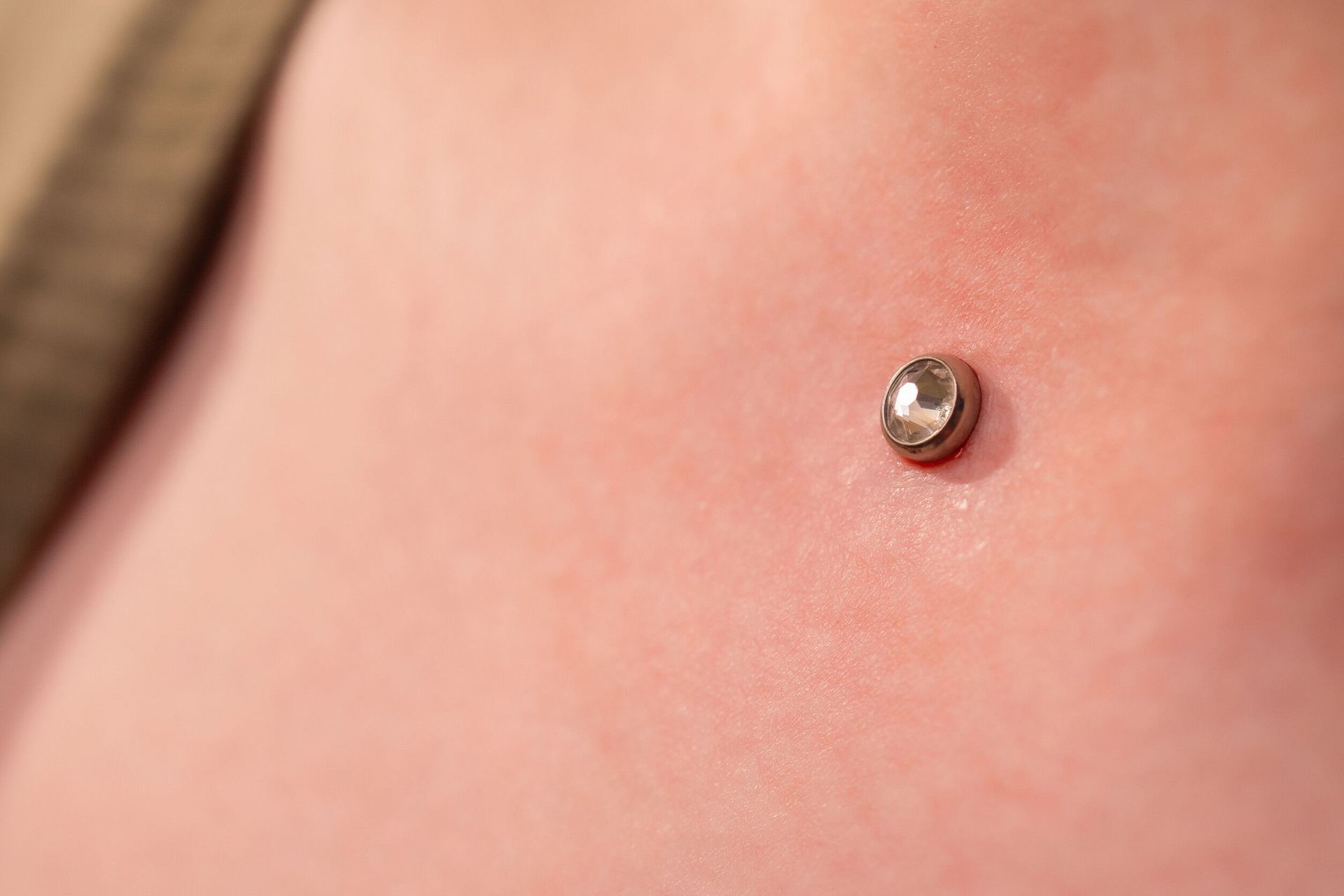 Un primer plano del pecho de una persona con un piercing.