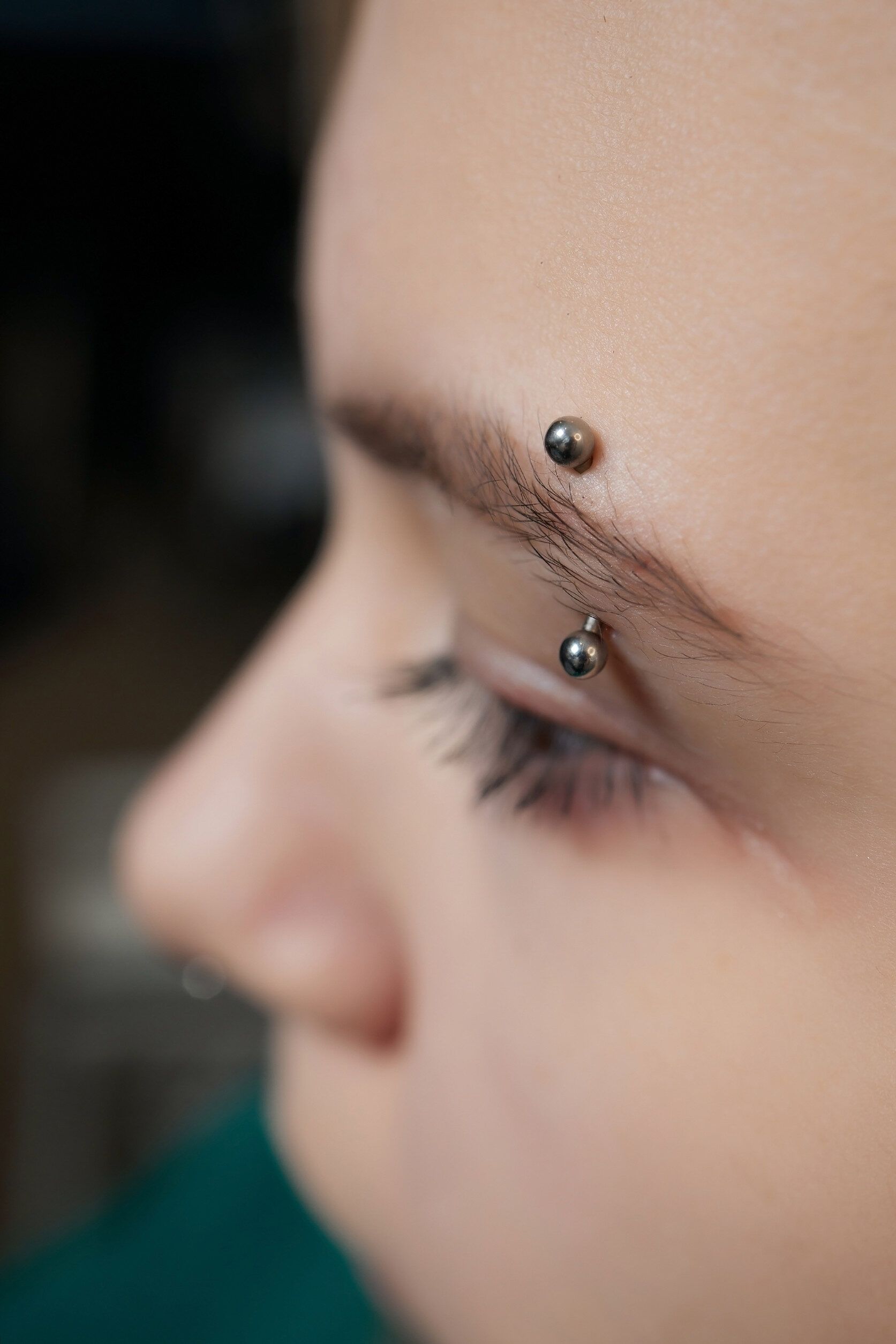 Un primer plano del rostro de una mujer con un piercing en la ceja.