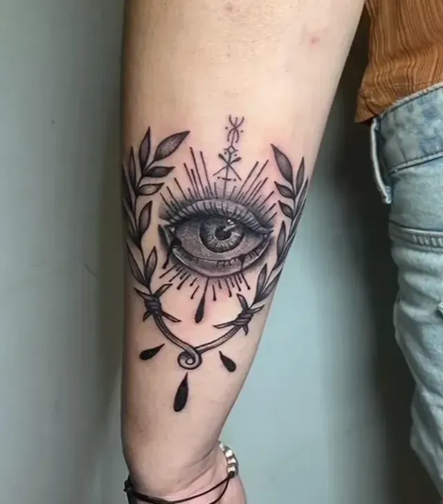 Una mujer tiene un tatuaje de un ojo que todo lo ve en su brazo.