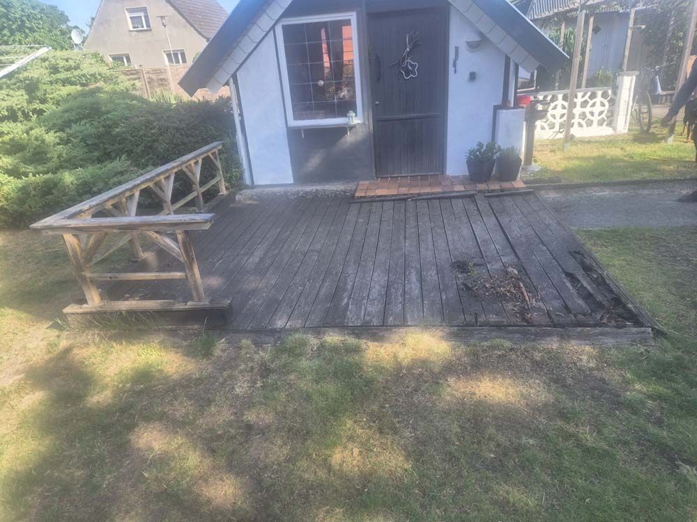 Ein kleines weißes Haus mit einer Holzterrasse davor.