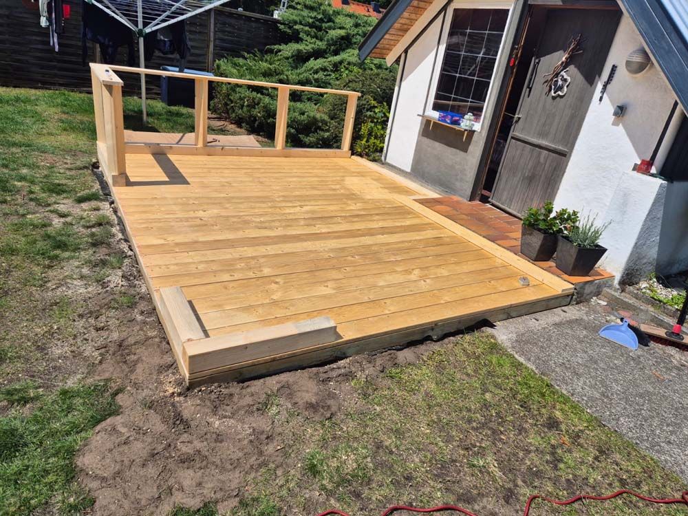 Vor einem kleinen Haus wird eine Holzterrasse gebaut.