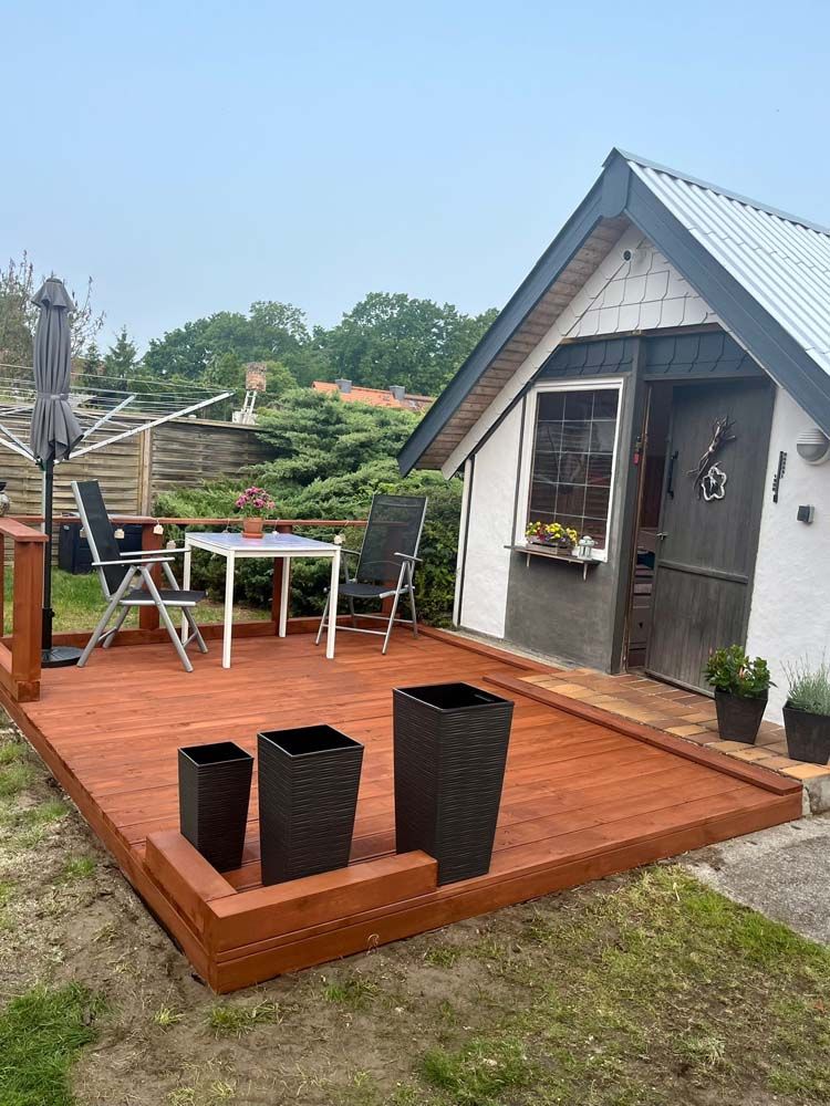 Ein kleines weißes Haus mit einer Holzterrasse davor.