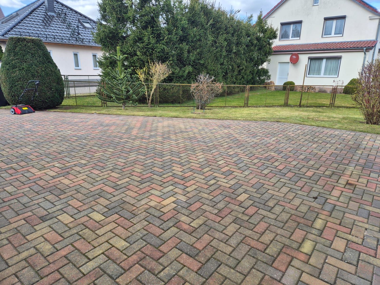 Eine gepflasterte Auffahrt mit einem Haus im Hintergrund.
