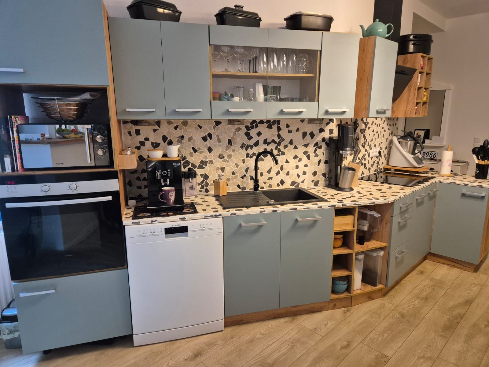 Eine Küche mit Spüle, Geschirrspüler, Backofen und Mikrowelle