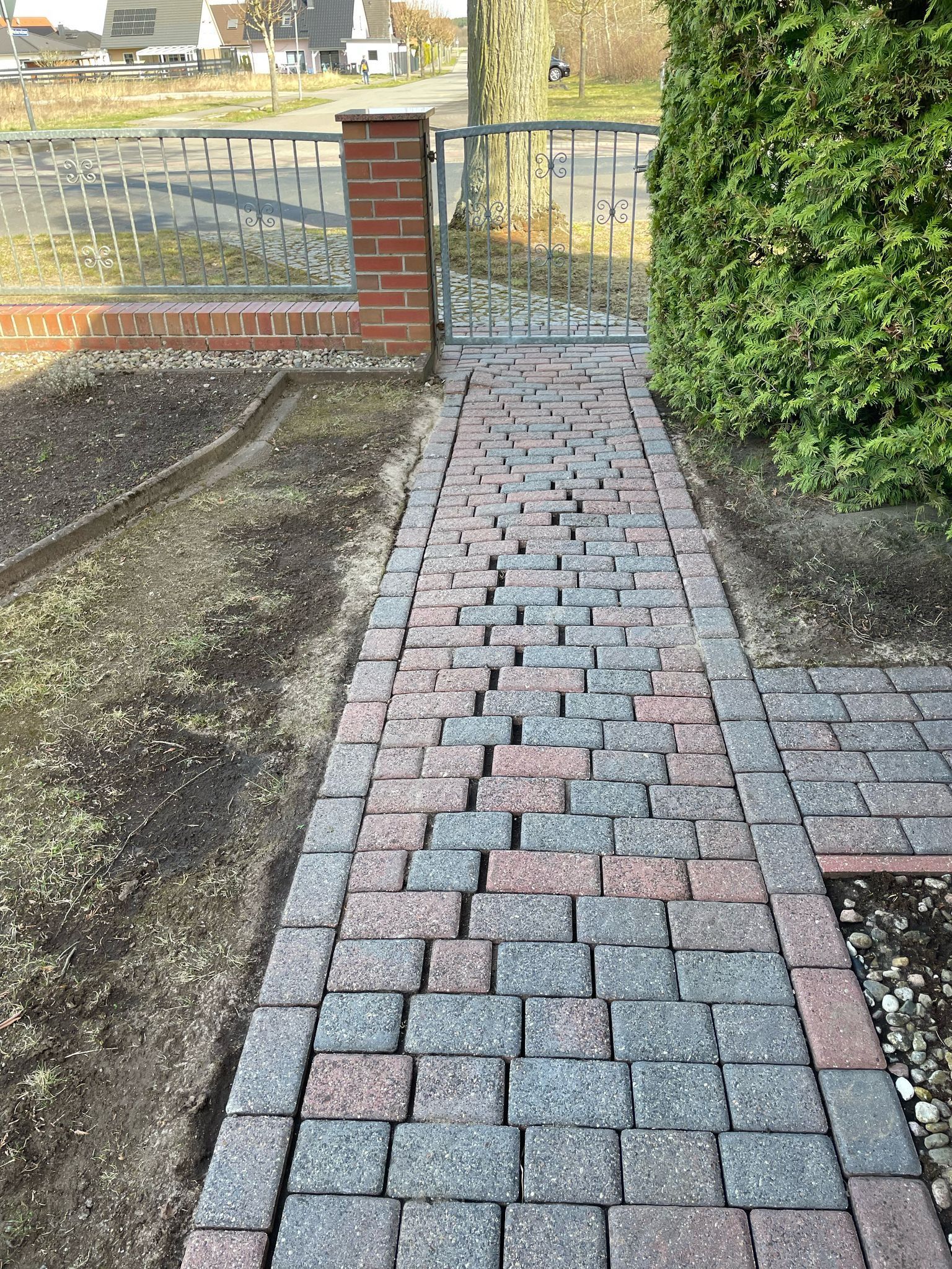 Ein gemauerter Gehweg, der zu einem Tor in einem Hof führt.
