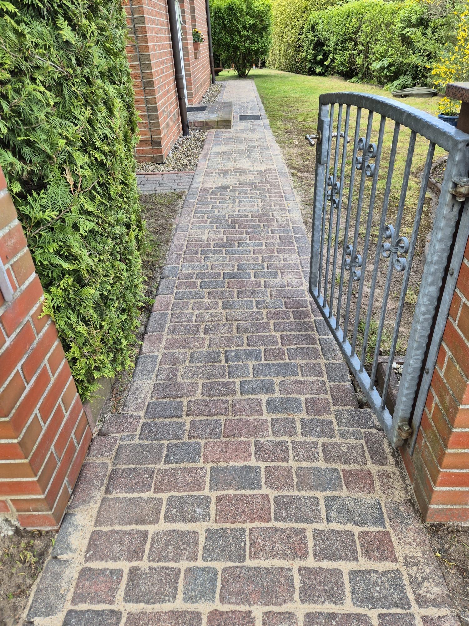 Ein gemauerter Gehweg, der zu einem Tor vor einem gemauerten Gebäude führt.