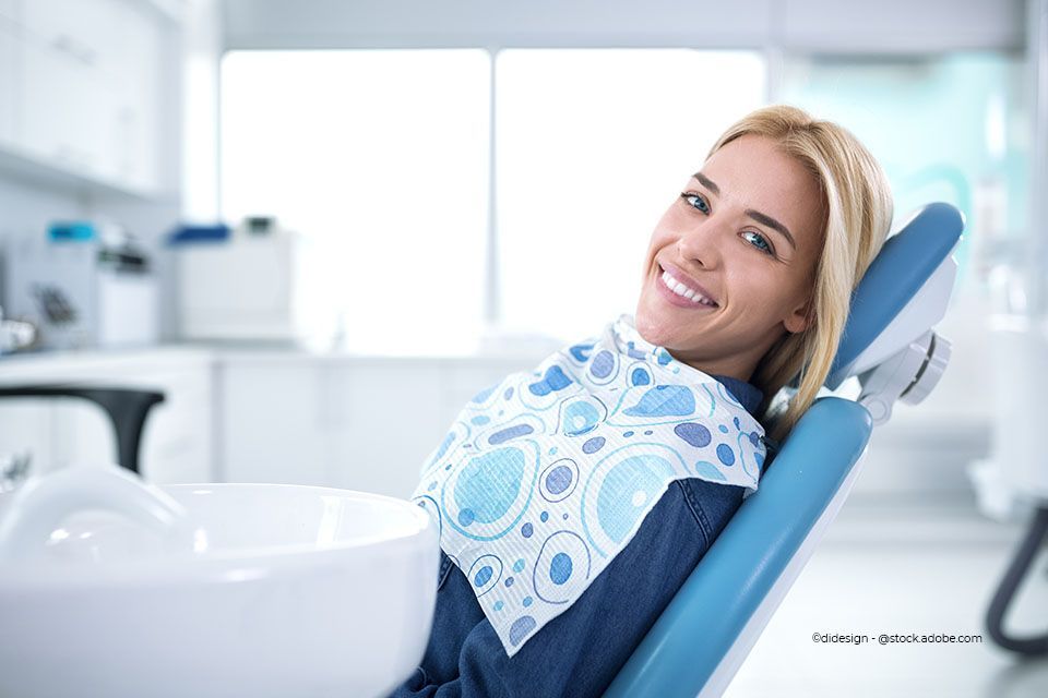 Patientin auf einem Zahnarztstuhl bei Zahnkompetenz Baramov liegend und in die Kamera lächelnd