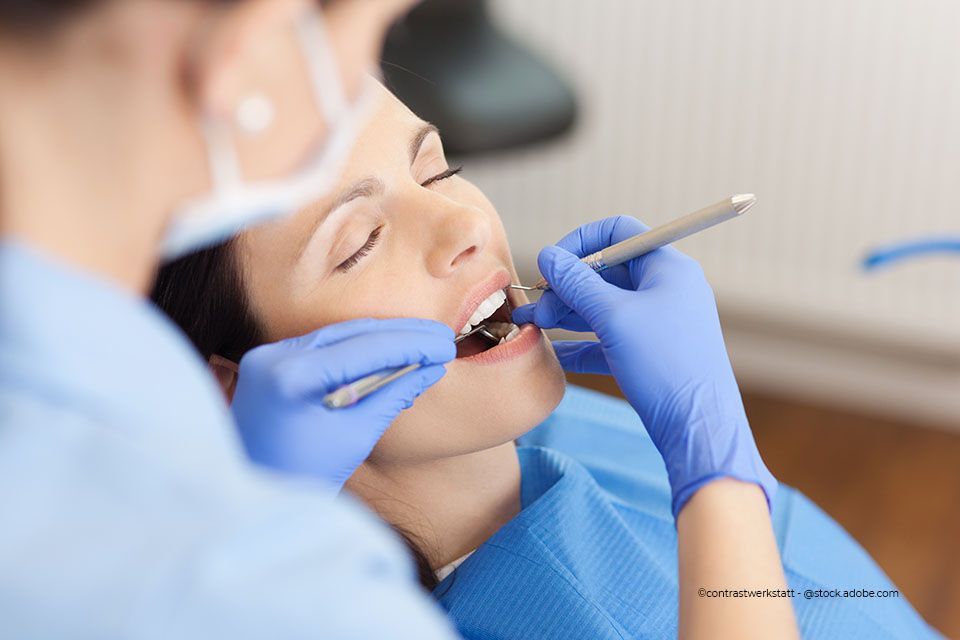 Der Zahnarzt von Zahnkompetenz Baramov untersucht die Zähne einer jungen Frau, die ihre Augen geschlossen hat