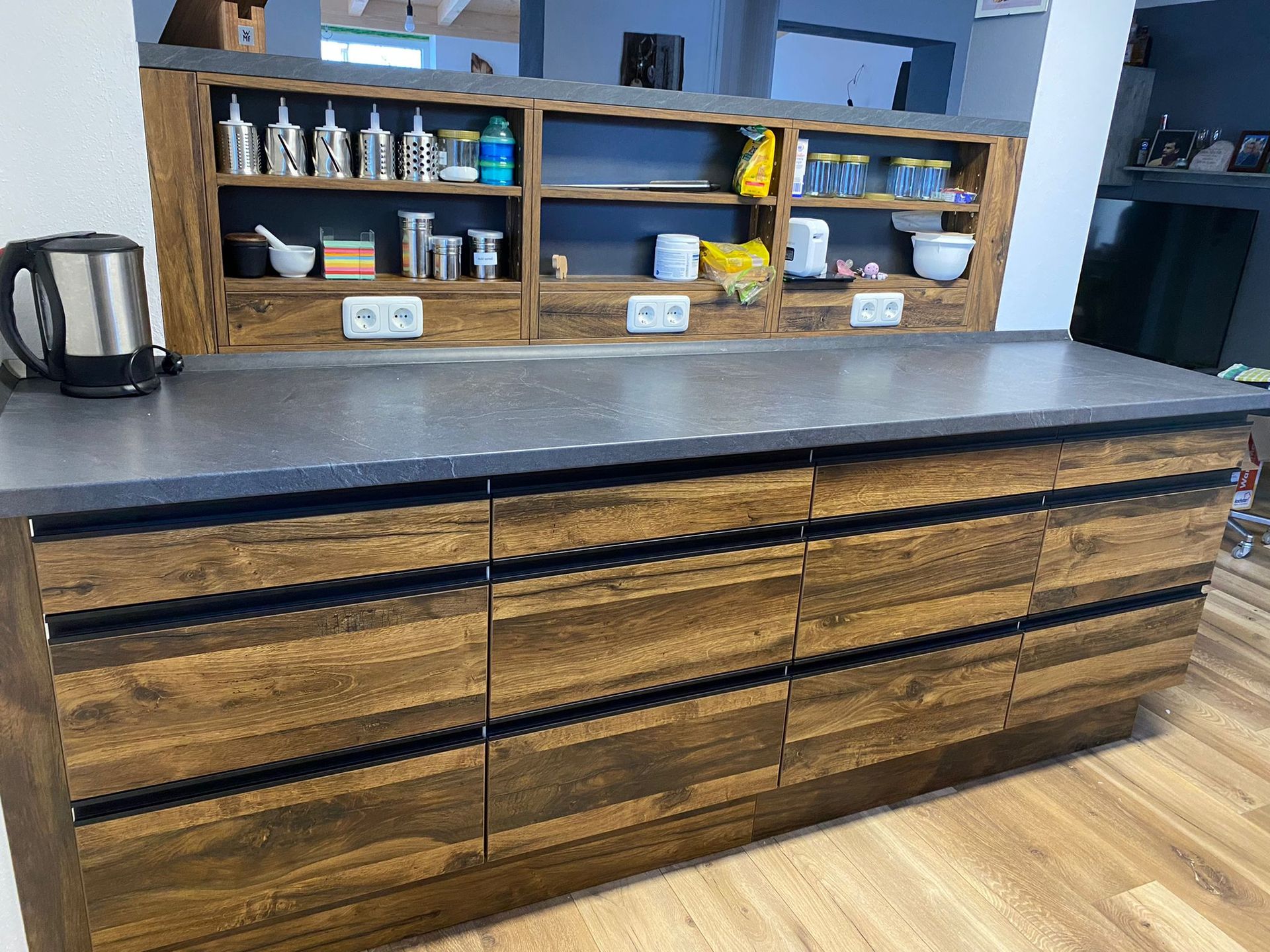 Küchenmodell Fischl Küchentresen aus Holz und integrierte Regale in der Wand darüber von Mihatho