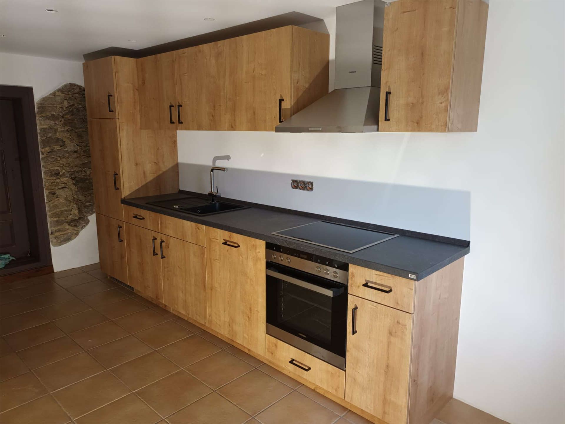 Kleine Einbauküche mit integriertem Kühlschrank und zweiter Küchenzeile mit Schränken auf der anderen Seite des Raumes