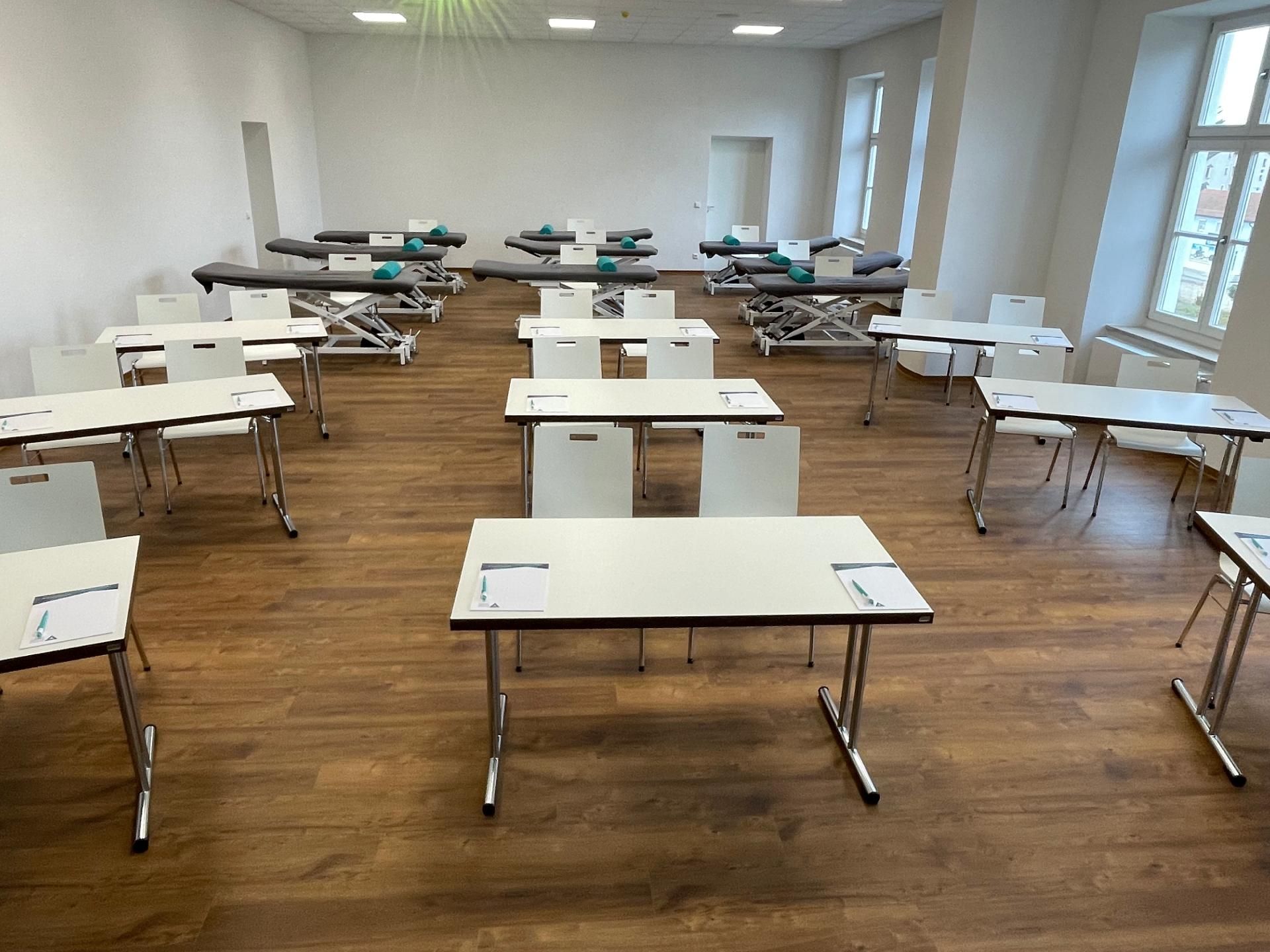 Einrichtung eines Seminarraumes mit Tischen, Stühlen und Krankenliegen von Mihatho