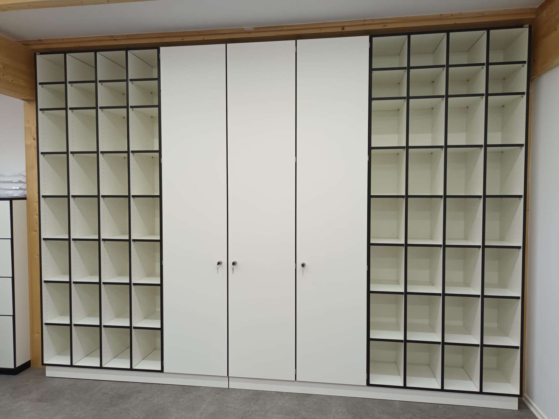 Schrankwand bei Aufzüge Tremmel mit vielen kleinen Fächern und Schranktüren