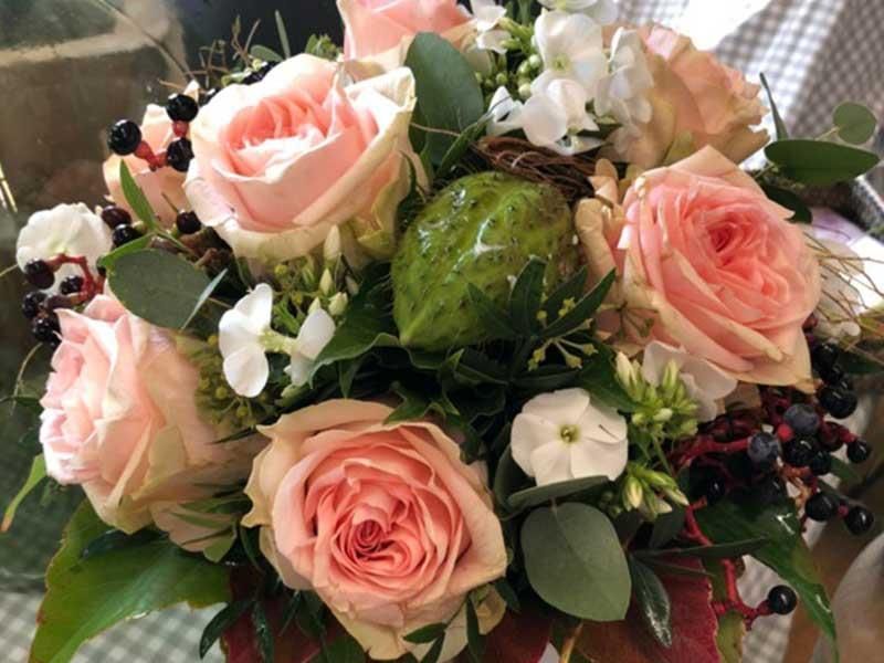 Auf einem Tisch steht ein Strauß rosa Rosen und weißer Blumen.