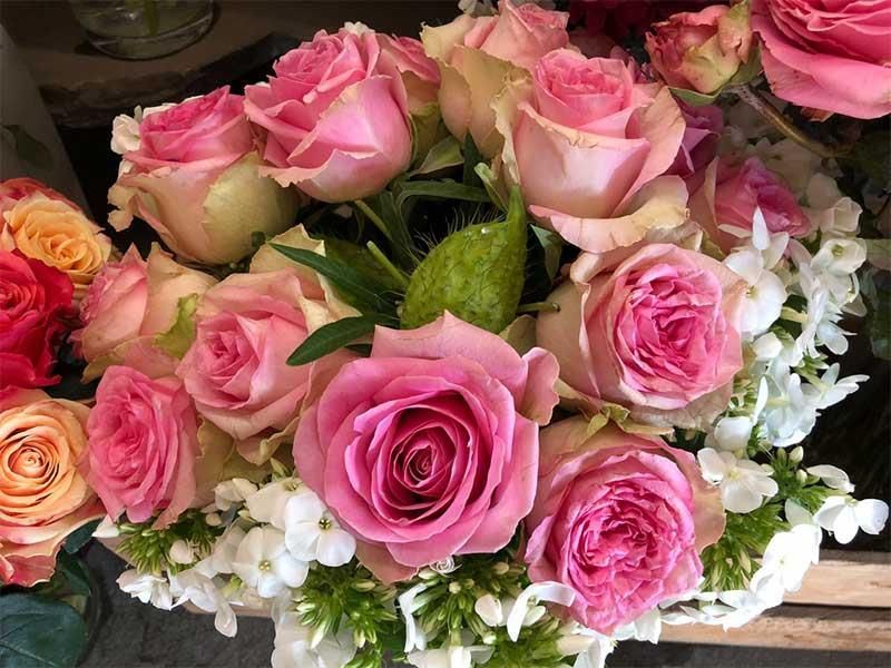 Ein Strauß rosa Rosen liegt auf einem Holztisch.