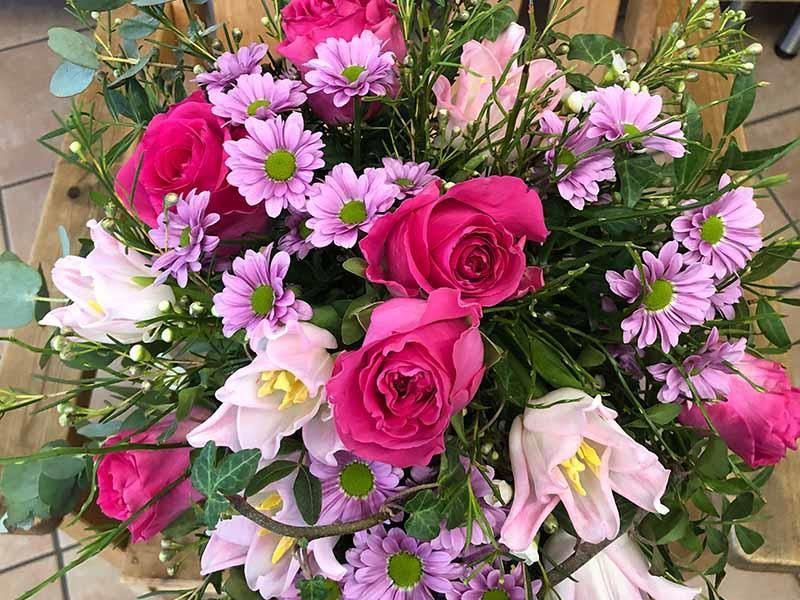 Ein Strauß rosa und lila Blumen steht auf einem Holztisch.