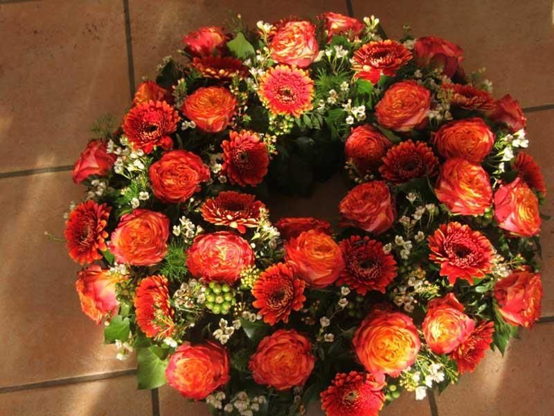 Ein Kranz aus roten Blumen liegt auf einem gefliesten Boden