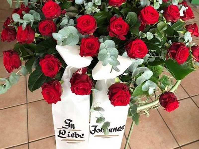 Ein Strauß roter Rosen mit einer weißen Schleife mit der Aufschrift „in Liebe Johannes“