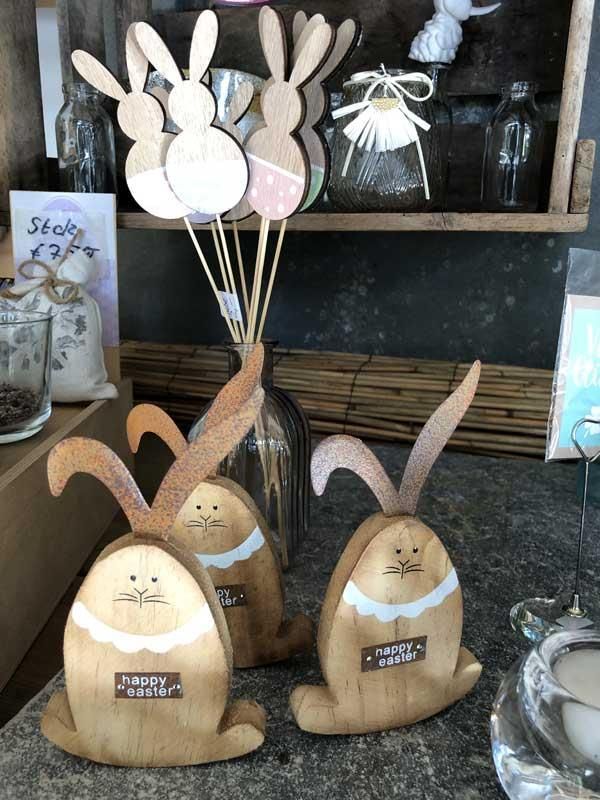 Drei hölzerne Hasenfiguren sitzen auf einem Tisch.