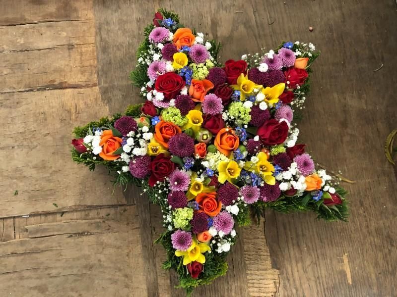 Ein Stern aus bunten Blumen auf einer Holzoberfläche