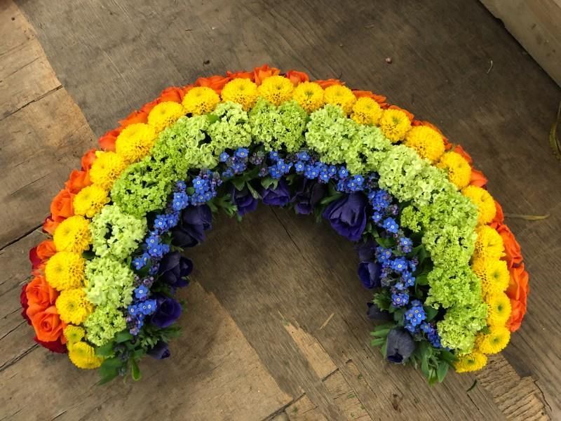 Ein Regenbogen aus Blumen auf einer Holzoberfläche
