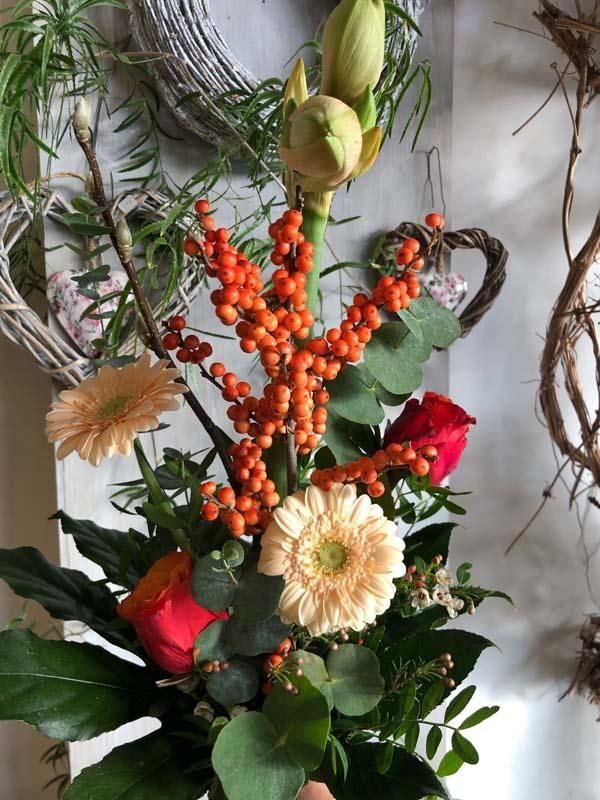 Ein Blumenstrauß mit Orangenbeeren und Rosen