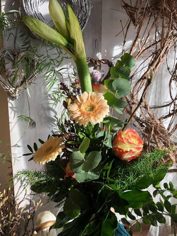 Ein Blumenstrauß steht auf einem Tisch vor einer Wand.