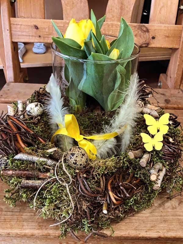 Ein Kranz mit Blumen und Federn auf einem Holztisch.