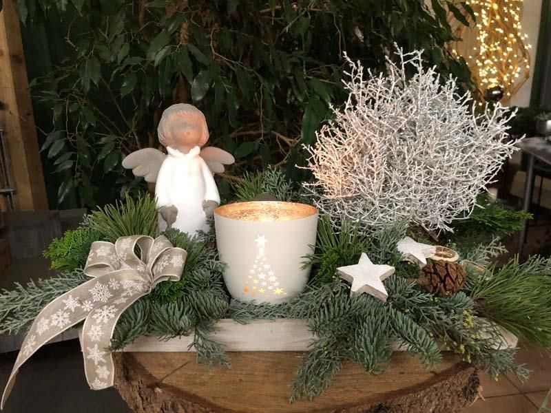 Auf einem Holztisch steht eine Kerze, umgeben von Weihnachtsdekorationen.