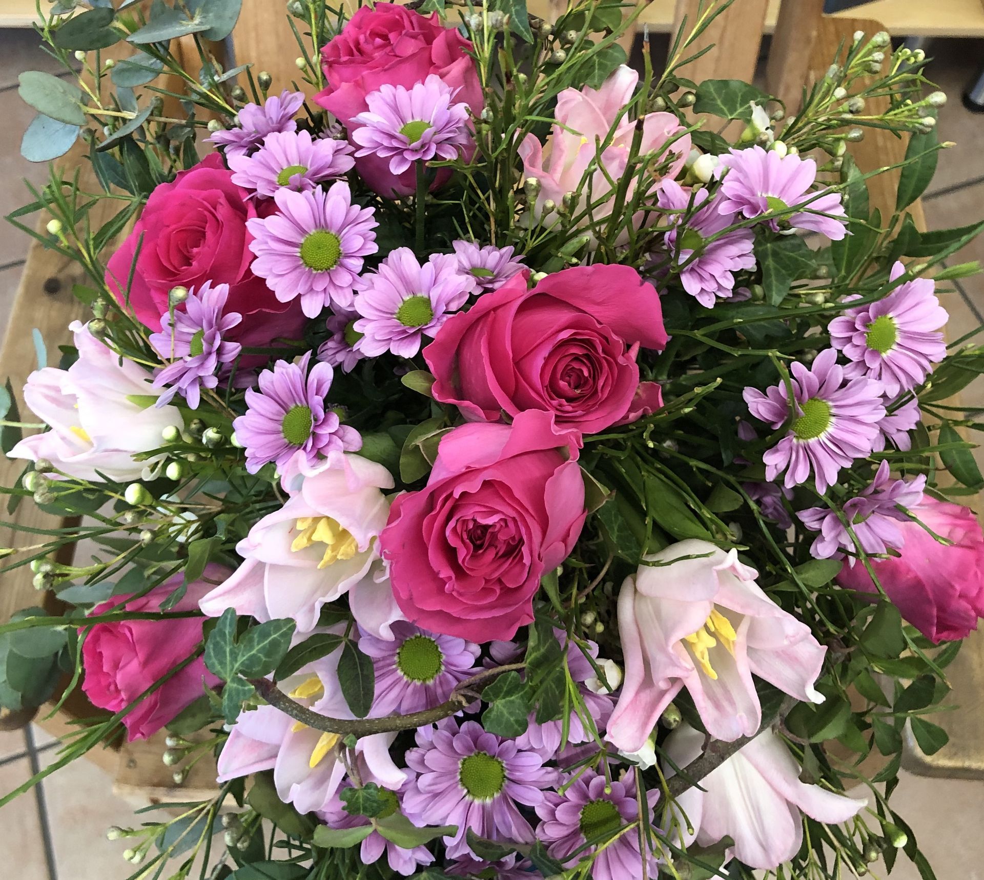 Eine Person schneidet mit einer Schere Blumen auf einem Holztisch.