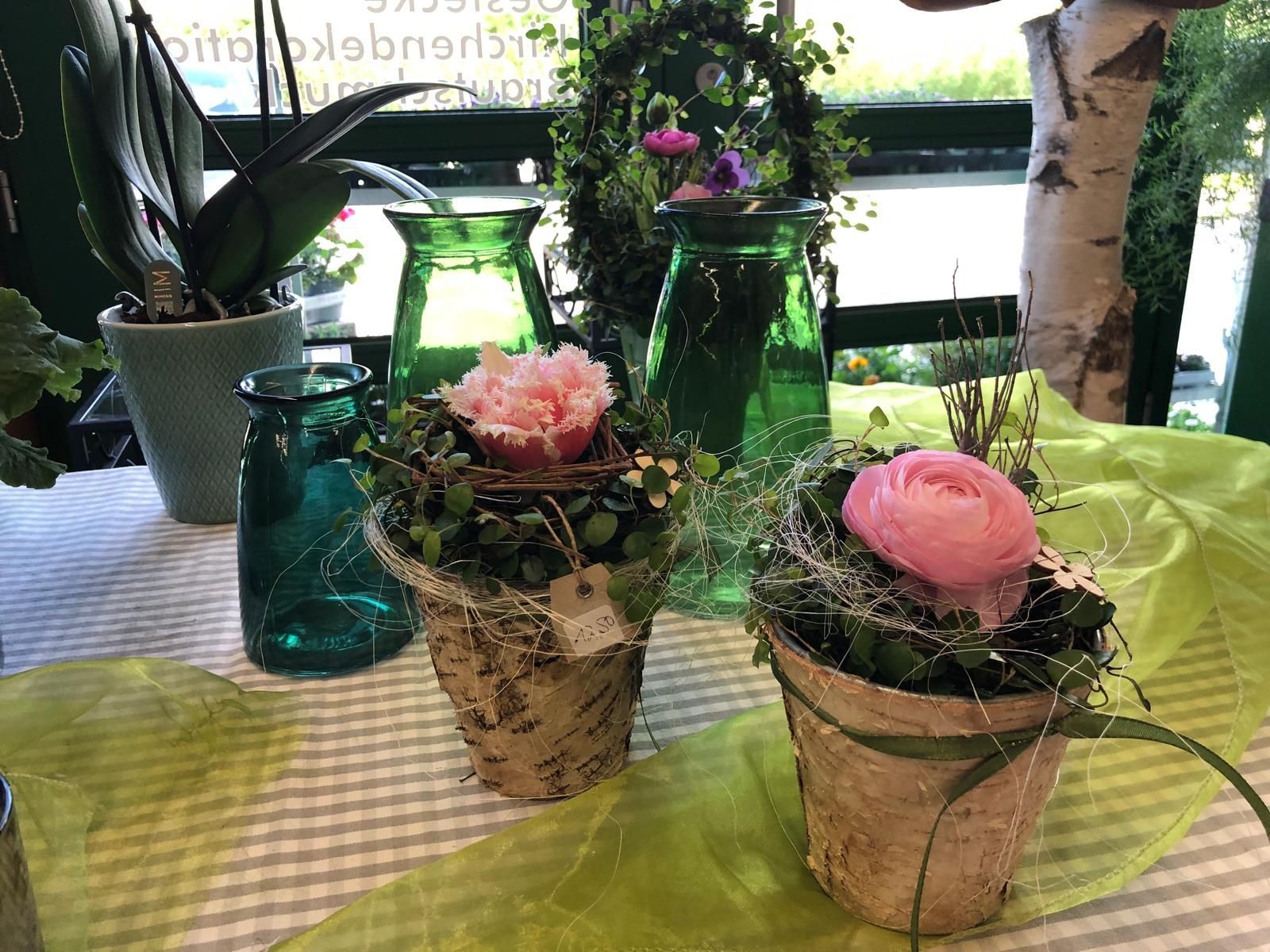 Ein Tisch mit Topfblumen und Vasen.