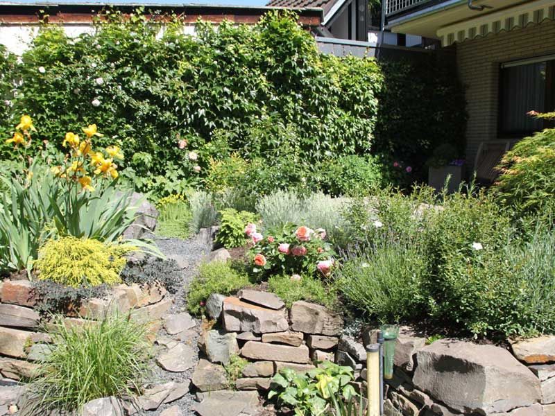 Ein Garten mit Blumen und Steinen vor einem Haus